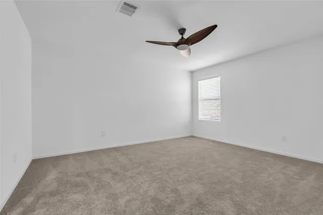 an empty room with a window and a ceiling fan