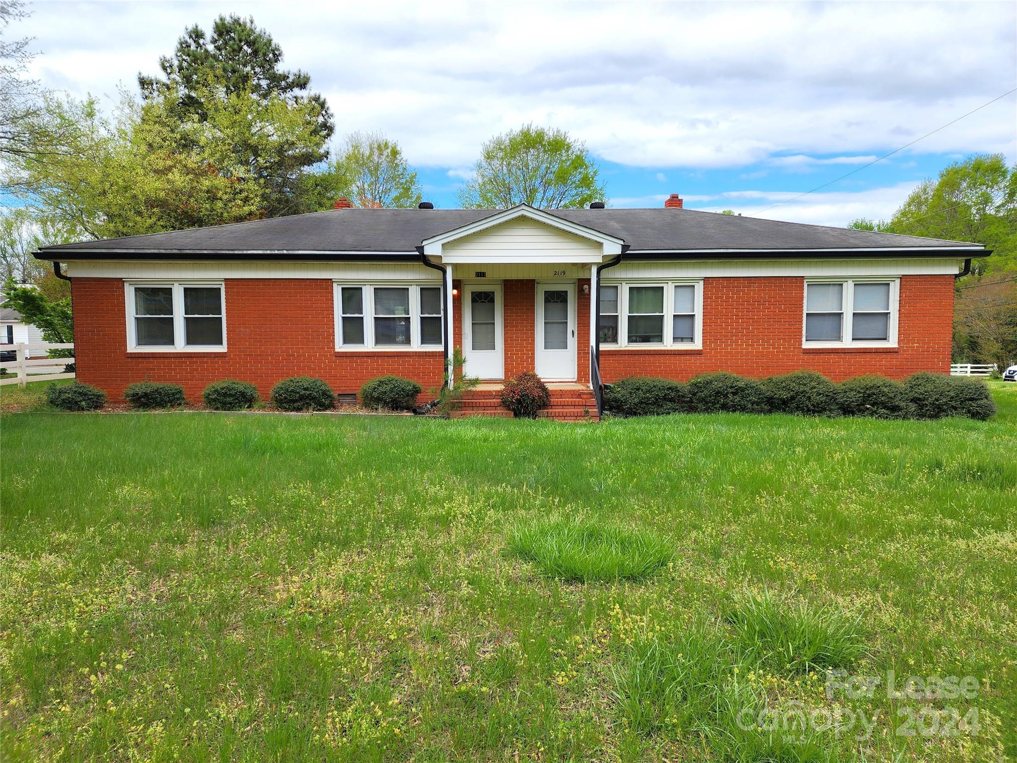 a front view of a house with a yard and green space
