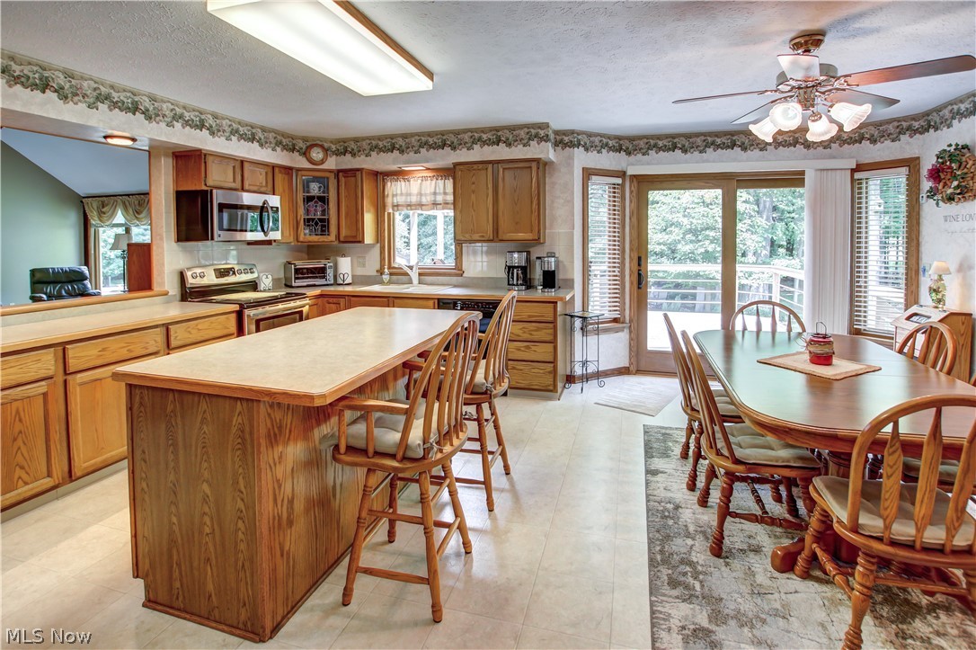 1010 Rustic Trail Cleveland, OH 44134 - Photo 6 of 49 Kitchen with a kitchen breakfast bar, a kitchen island, appliances with stainless steel finishes, light tile flooring, and ceiling fan