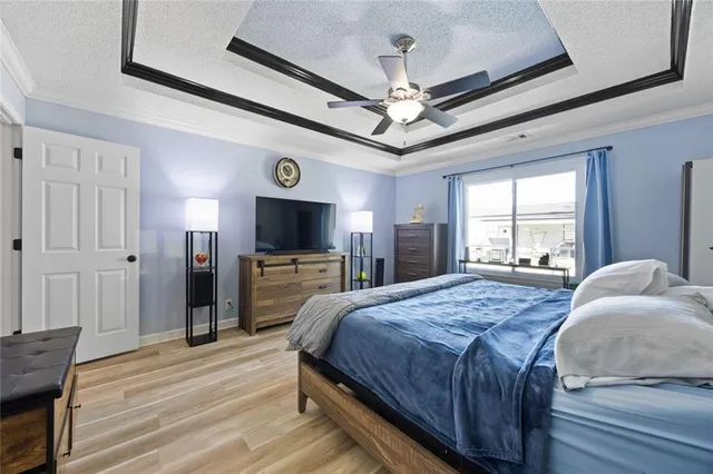 a bedroom with a bed a tv and wooden floor