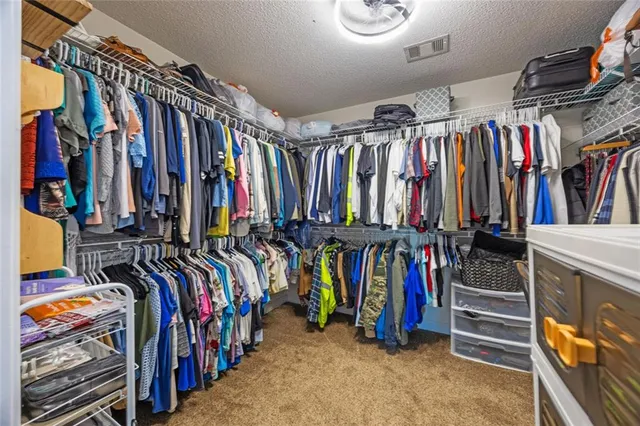 a view of walk in closet with clothes and shoes