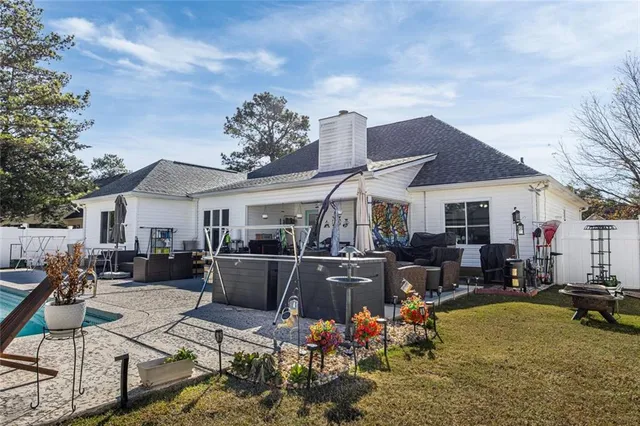 a view of a white house with couches chairs and a barbeque