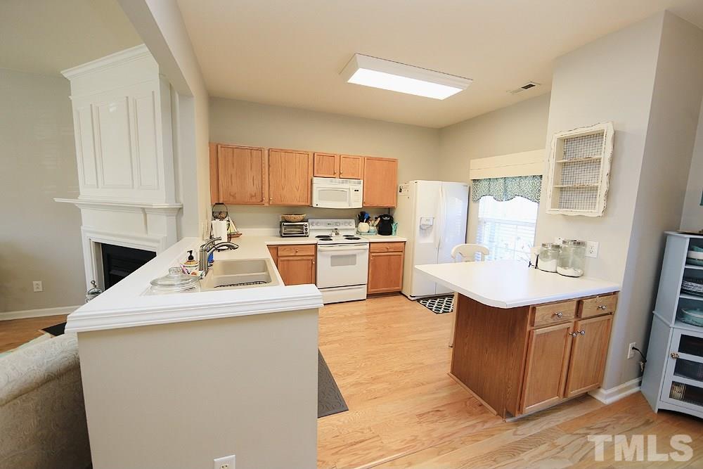 5013 Echo Ridge Road Raleigh, NC 27612 - Photo 5 of 15 a kitchen with a sink a stove a refrigerator cabinets and a dining table