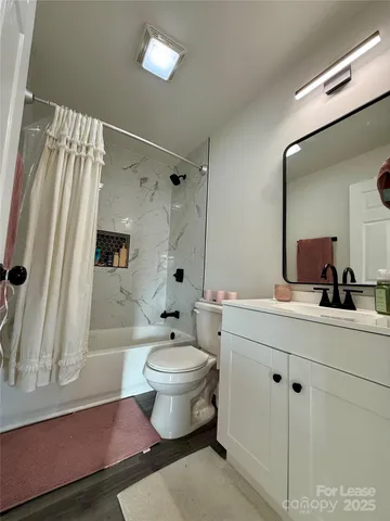 a spacious bathroom with a double vanity sink a toilet a mirror and shower