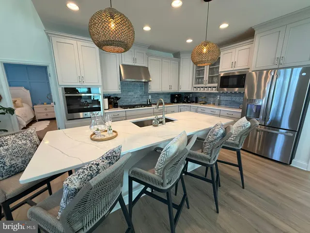 a kitchen with stainless steel appliances granite countertop a sink a stove a kitchen island with chairs and wooden floor