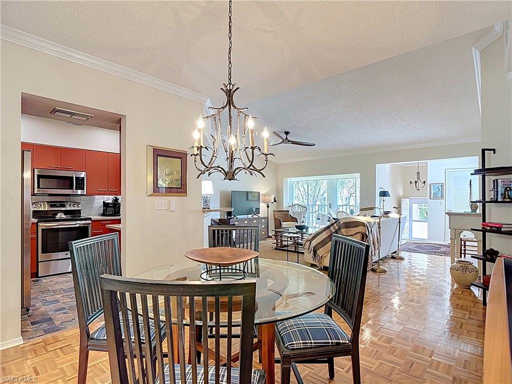 106 Siena Way, Unit 1508 Naples, FL 34119 - Photo 15 of 47 a view of a dining room with furniture wooden floor and chandelier
