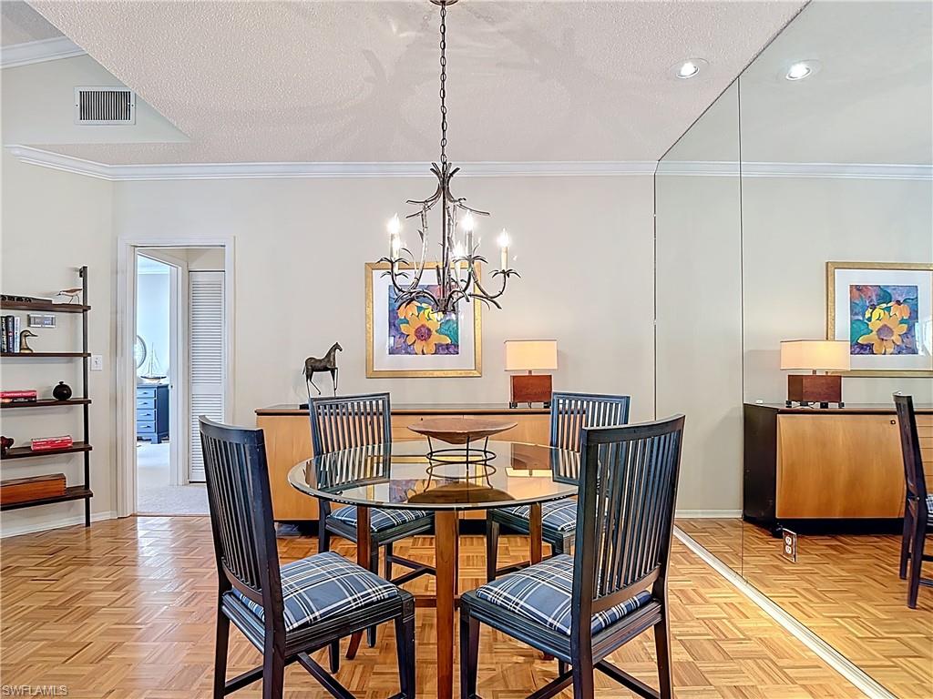 106 Siena Way, Unit 1508 Naples, FL 34119 - Photo 16 of 47 a view of a dining room with furniture and wooden floor