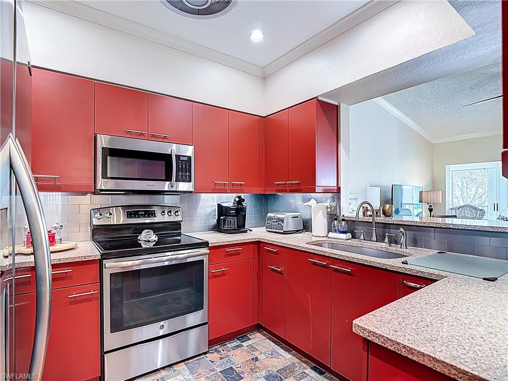 106 Siena Way, Unit 1508 Naples, FL 34119 - Photo 18 of 47 a kitchen with stainless steel appliances kitchen island granite countertop a sink dishwasher stove and microwave with wooden cabinets