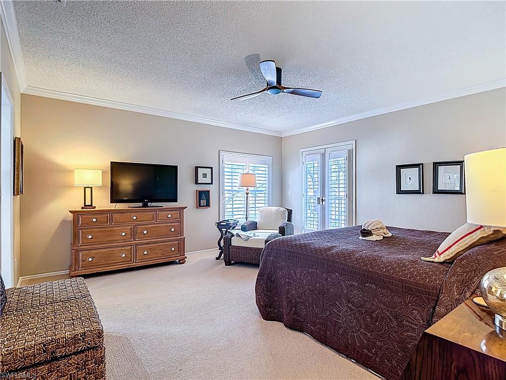 106 Siena Way, Unit 1508 Naples, FL 34119 - Photo 22 of 47 a bedroom with a bed a couch and a flat screen tv