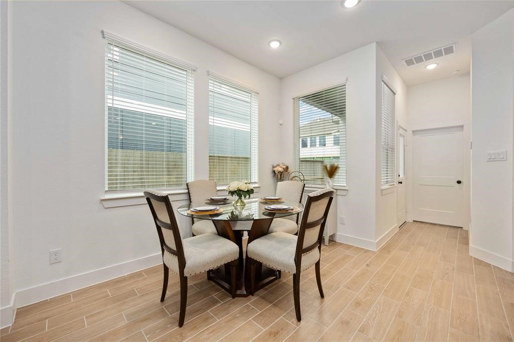 10014 Nectar Path Iowa Colony, TX 77583 - Photo 7 of 26 Bright and inviting dining area with large windows, stylish tile flooring, and a cozy four-seater table setting, perfect for intimate meals.