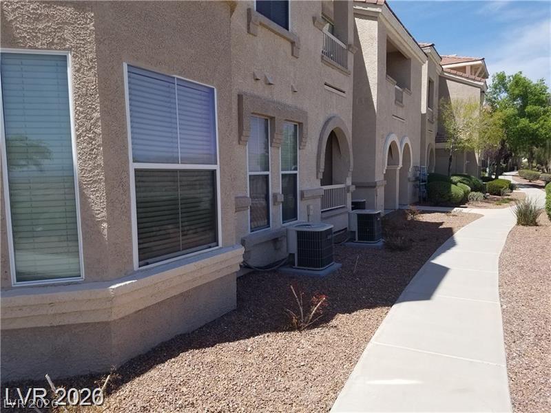 10550 West Alexander Road, Unit 1040 Las Vegas, NV 89129 - Photo 7 of 18 A concrete pathway winds past the textured stucco exterior under clear blue skies.