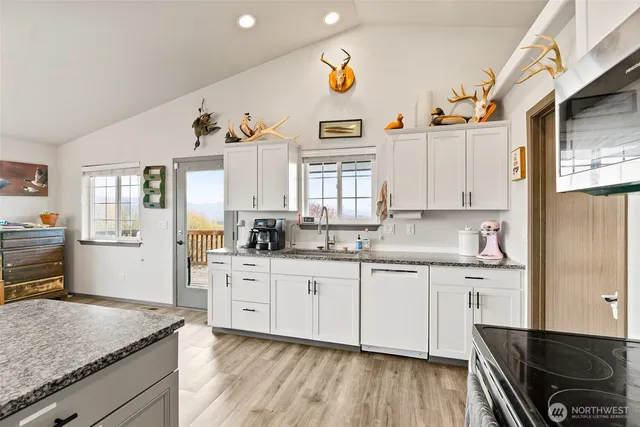 a kitchen with granite countertop a sink cabinets and wooden floor