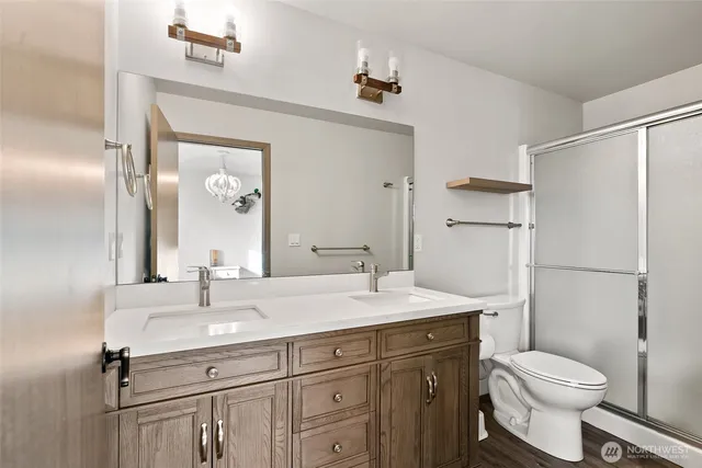 a bathroom with a sink a toilet a mirror and shower