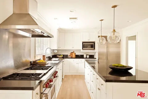 a kitchen with stainless steel appliances granite countertop a stove a sink and a refrigerator