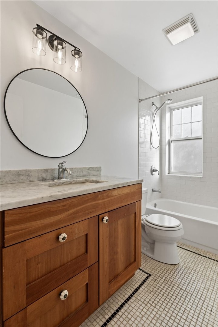 4420 North Ashland Avenue, Unit 3E Chicago, IL 60640 - Photo 12 of 15 a bathroom with a granite countertop toilet a sink and a mirror