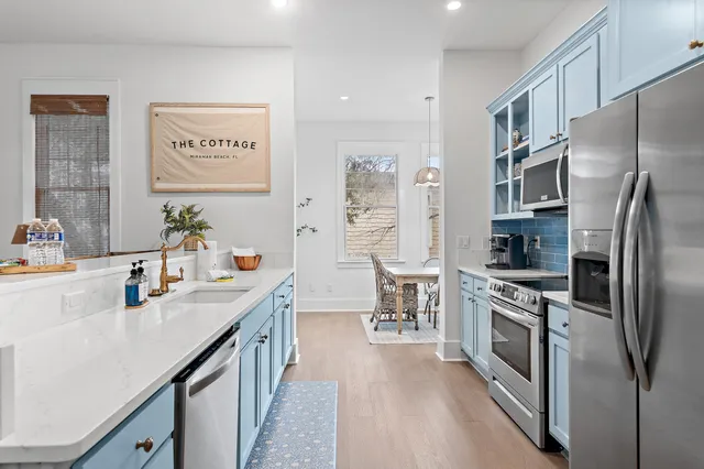 a kitchen with stainless steel appliances a refrigerator a sink a stove and white cabinets