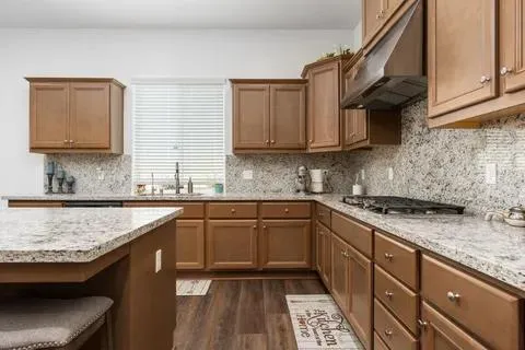 a kitchen with granite countertop a sink stove and cabinets