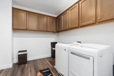 a utility room with wooden floor washer and dryer