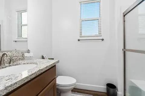 a bathroom with a granite countertop sink toilet and a mirror