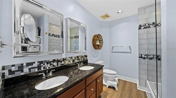 a bathroom with a granite countertop sink a toilet a mirror and shower