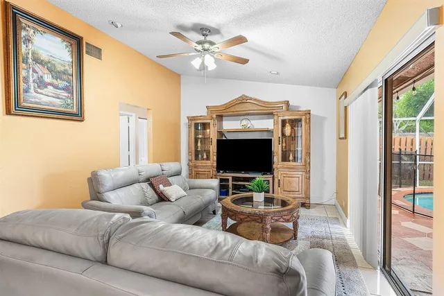a living room with furniture a ceiling fan and a large window