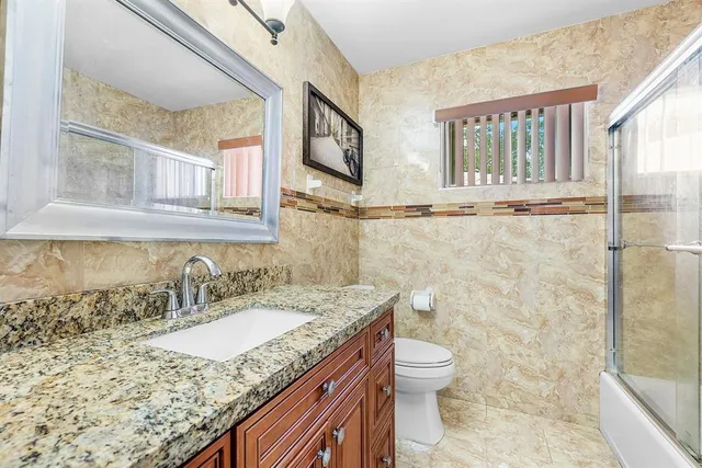 a bathroom with a granite countertop sink toilet and shower