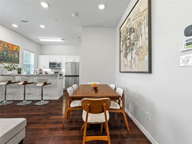a living room with stainless steel appliances furniture and a wooden floor
