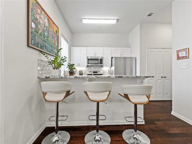 a kitchen with stainless steel appliances granite countertop a dining table chairs and granite counter tops