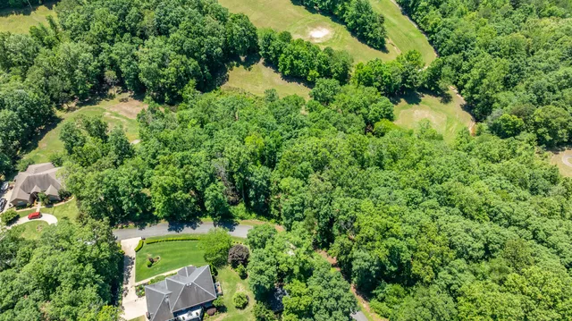 an aerial view of residential house with outdoor space and trees all around