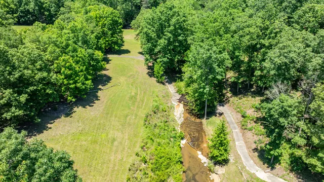 an aerial view of residential house with outdoor space and trees all around