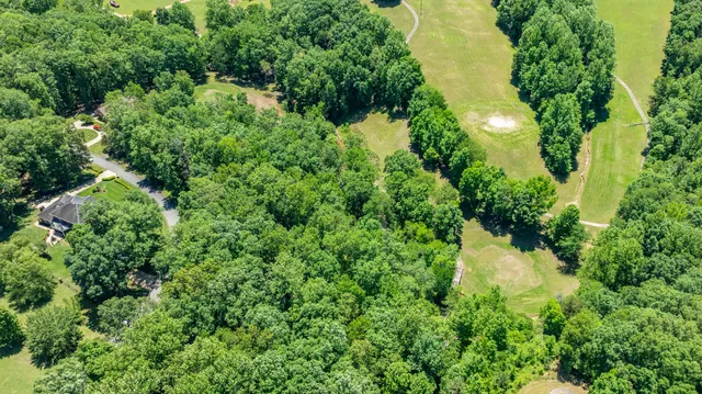 an aerial view of residential house with outdoor space and trees all around