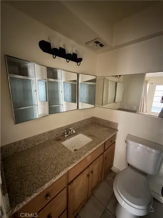 a bathroom with a granite countertop sink a toilet a mirror and shower
