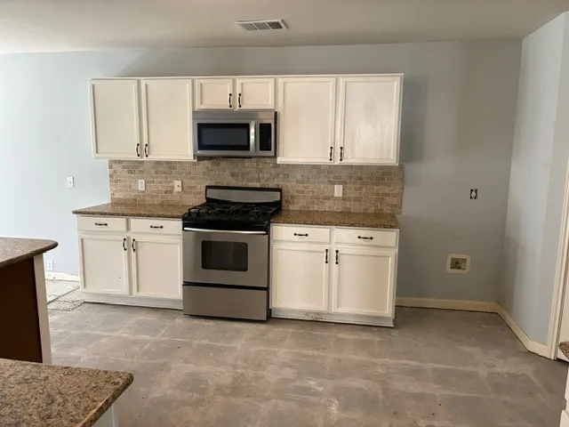 a kitchen with white cabinets and appliances