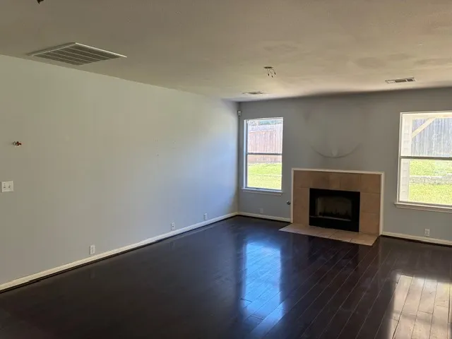 an empty room with wooden floor a fireplace and windows