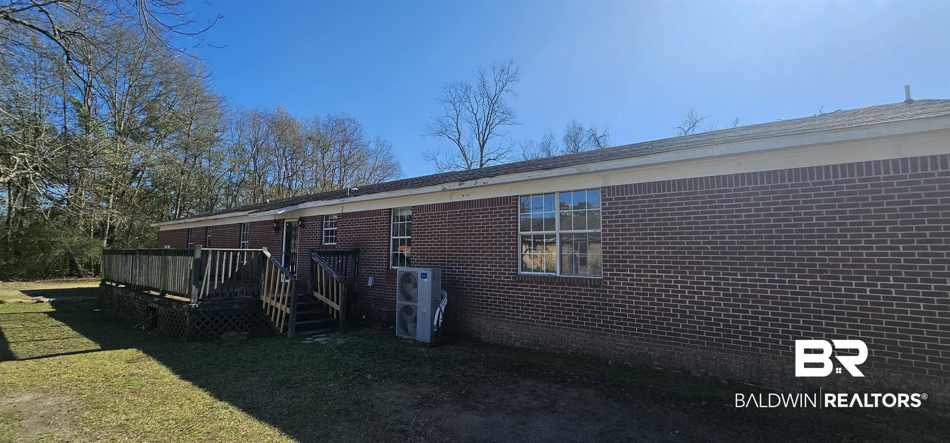 151 Bullard Street Atmore, AL 36502 - Photo 36 of 38 Rear view of property featuring brick siding, a wooden deck, and a lawn
