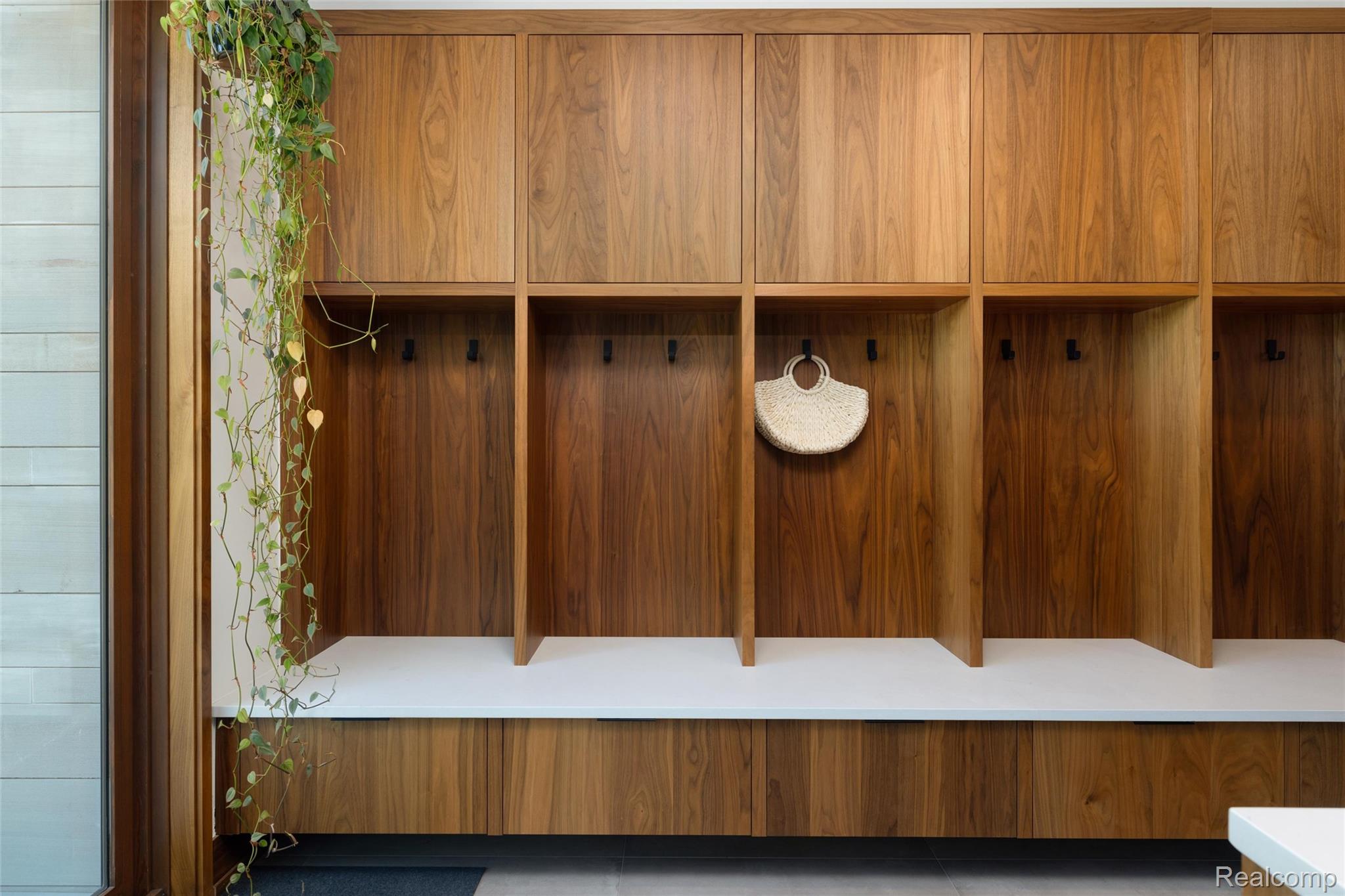 2700 Squirrel Road Bloomfield Hills, MI 48304 - Photo 21 of 83 Custom built-in entryway storage featuring wood-finish cabinetry, integrated open cubbies, individual black coat hooks, and a continuous white bench seat