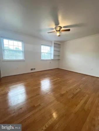 an empty room with wooden floor chandelier fan and windows