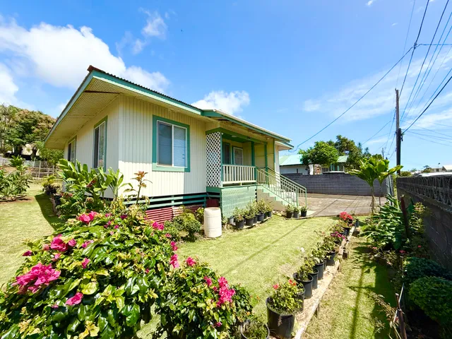 a front view of house and yard with beautiful flowers