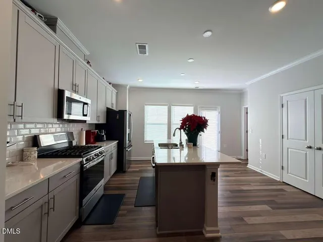 a kitchen with stainless steel appliances granite countertop a refrigerator a stove top oven a sink dishwasher and wooden floor