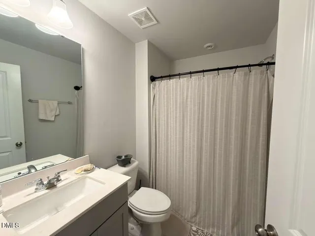 a bathroom with a sink a toilet and shower curtain