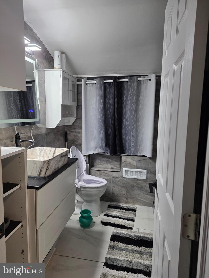 1407 Adamsview Road Baltimore, MD 21228 - Photo 20 of 40 a bathroom with a sink a toilet and mirror