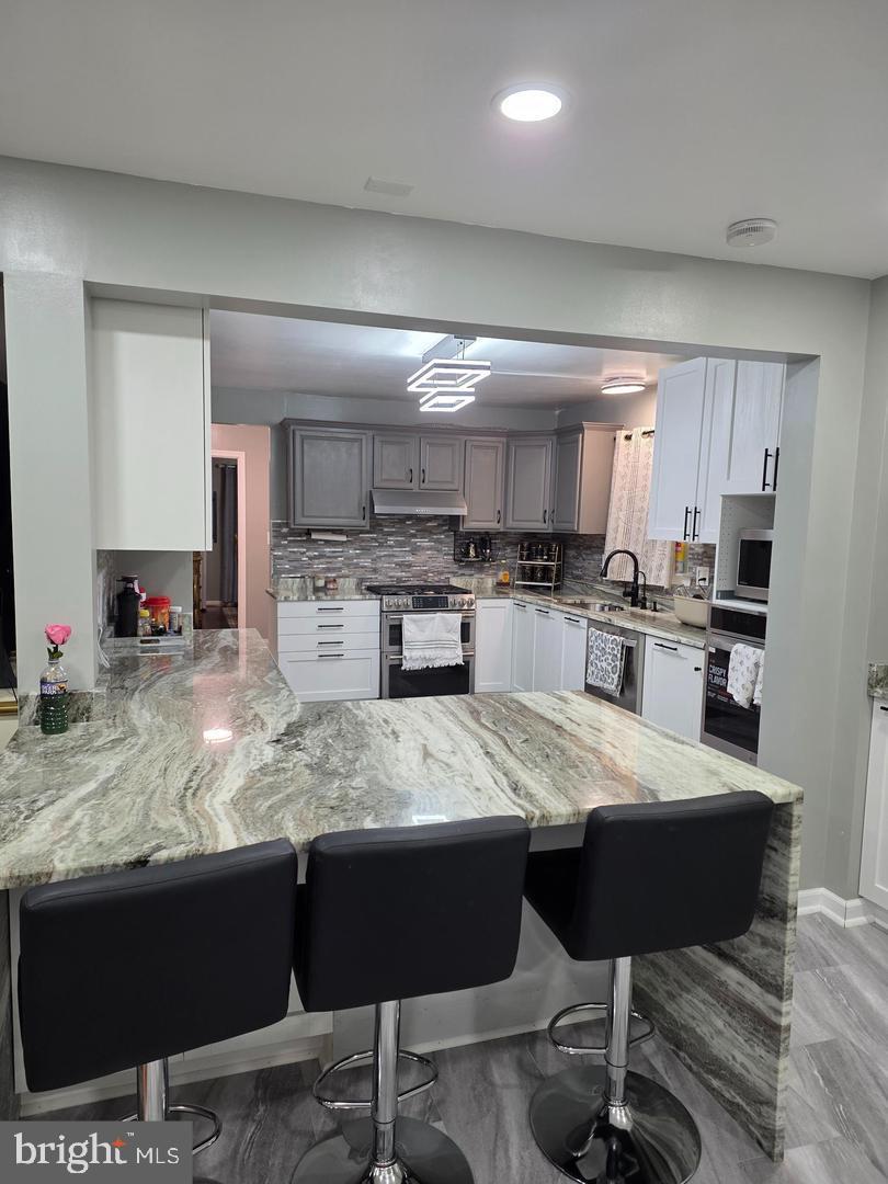 1407 Adamsview Road Baltimore, MD 21228 - Photo 9 of 40 a large kitchen with granite countertop lots of counter top space and appliances