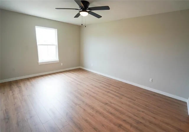 a view of an empty room with wooden floor and window