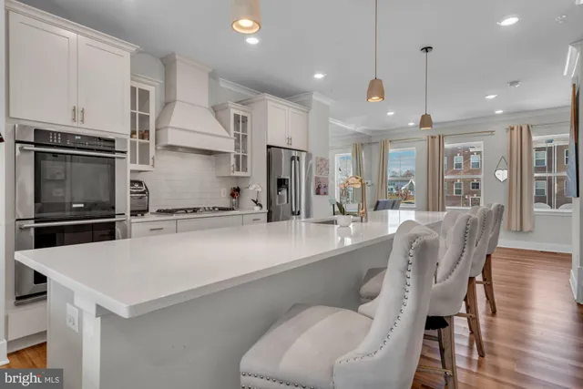 a kitchen with stainless steel appliances granite countertop a refrigerator a sink dishwasher a stove and a refrigerator with wooden floor