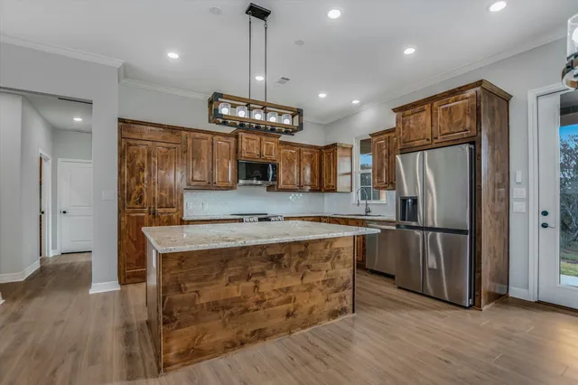 a kitchen with stainless steel appliances granite countertop a refrigerator a sink and a stove