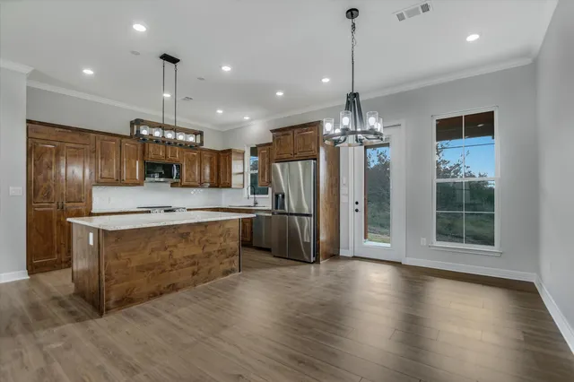 a large kitchen with granite countertop a large counter top a sink stainless steel appliances and cabinets