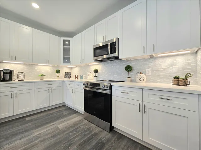 a kitchen with stainless steel appliances granite countertop white cabinets a sink and dishwasher