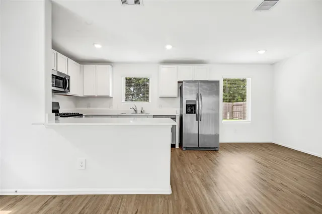 a kitchen with granite countertop a refrigerator a sink a stove a microwave and wooden floor