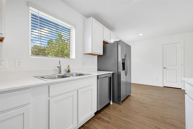 a kitchen with a sink cabinets stainless steel appliances and a window