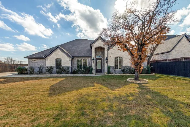 a front view of a house with yard and tree